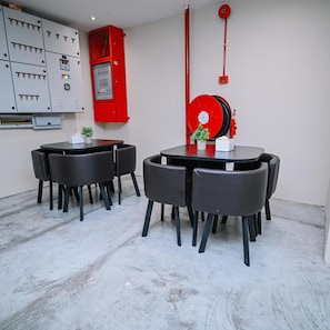 A conference room with a table and chairs, a red fire extinguisher, and electrical panels on the wall. - Swing & Pillows @ Putrajaya (Putrajaya)