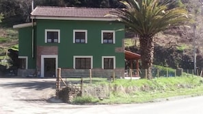A two-story building with a green facade, a brick entrance, and a covered porch area. - Hotel Penacabrera 1 (Santa Eulalia de Oscos)