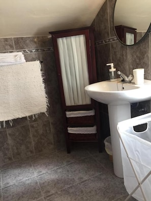 A bathroom with a white sink, a mirror above it, and a towel rack with towels. - Hotel Penacabrera 1 (Santa Eulalia de Oscos)