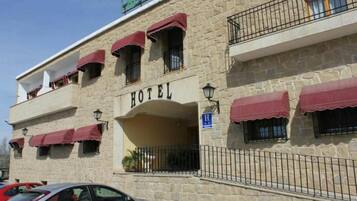 Un edificio de piedra con un letrero que dice 'HOTEL' y un letrero azul que indica una entrada accesible para personas con discapacidad.