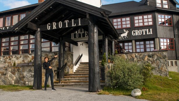 Ein Holzgebäude mit einem Schild, auf dem 'GROTLI HOTEL' steht, und einem Hirsch-Symbol.