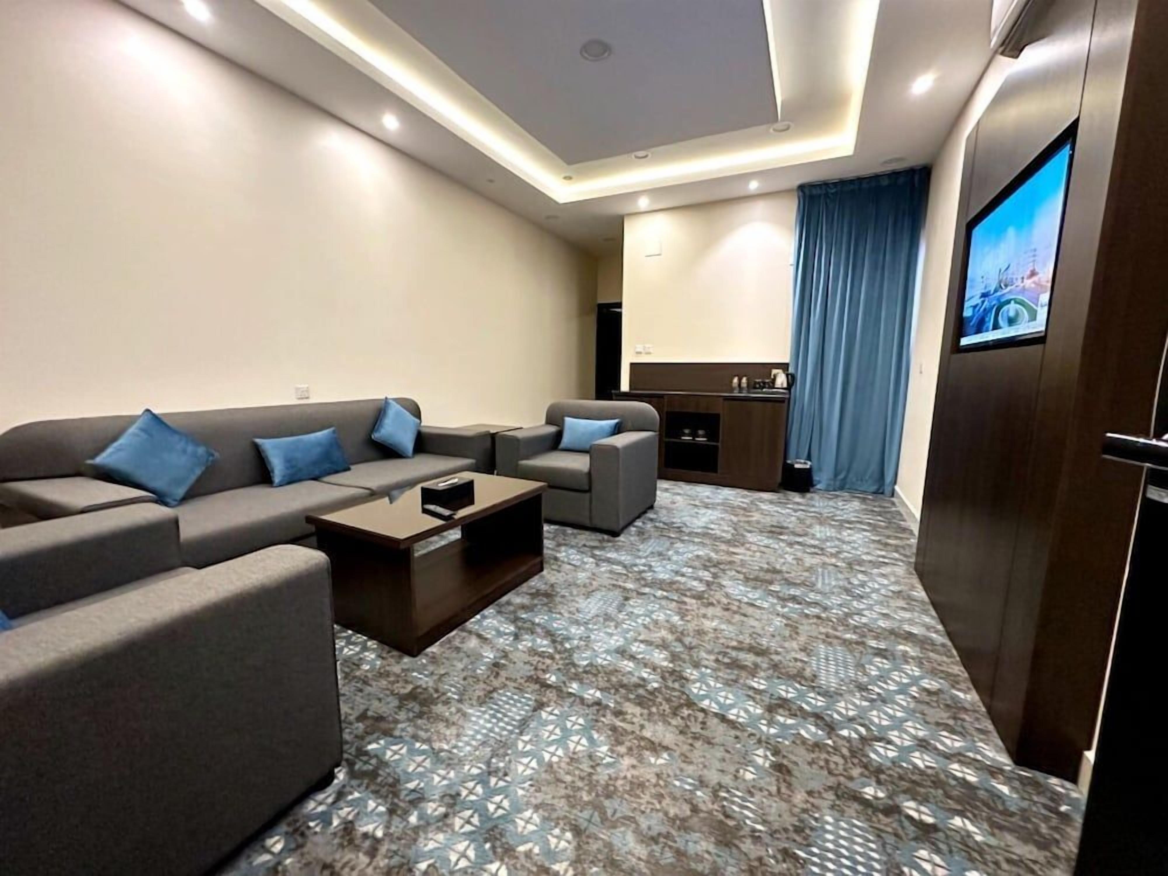 A modern living room with a sofa set, a coffee table, and a television mounted on the wall.