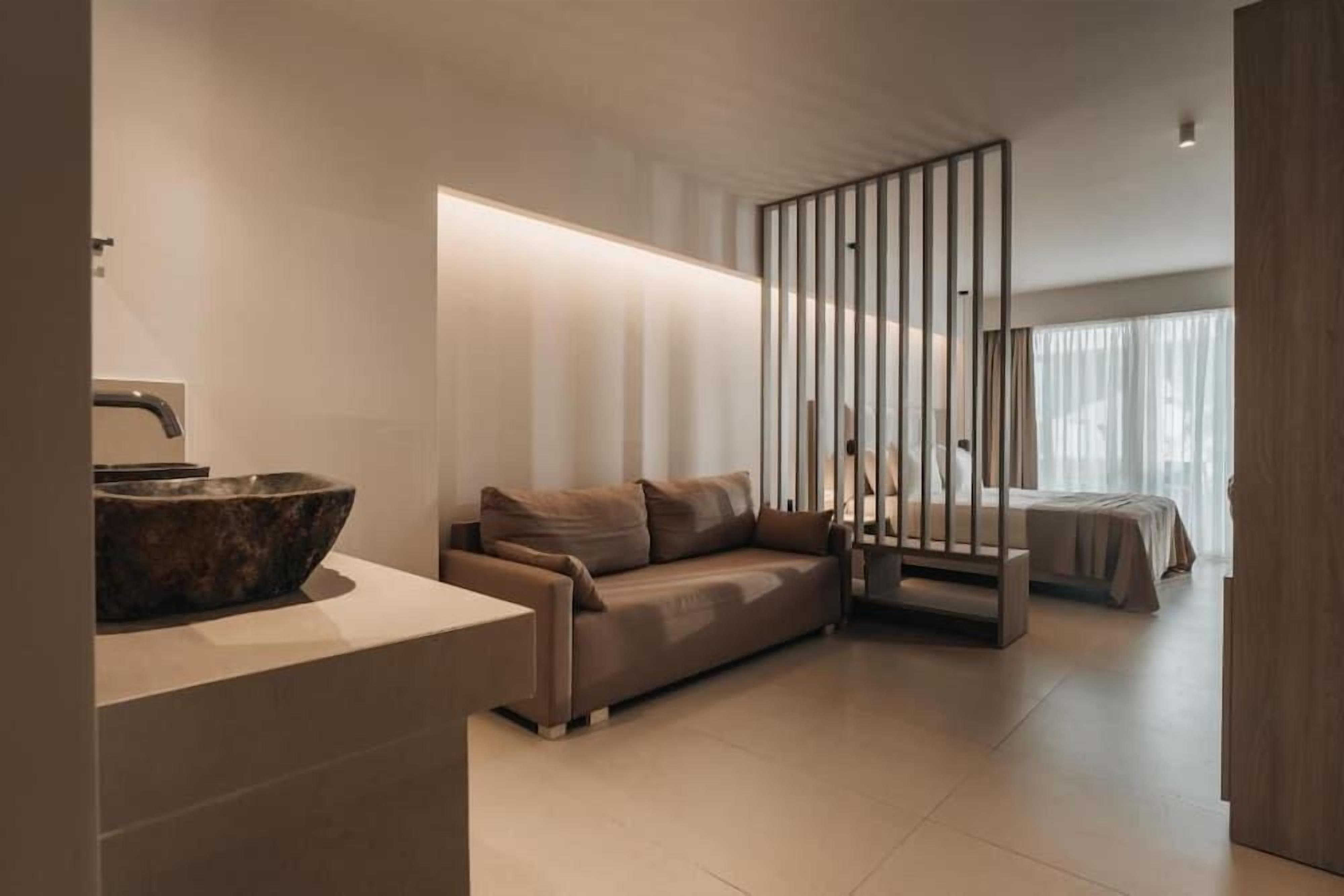 Een modern interieur met een bank, een houten bijzettafeltje, een grote schaal en een bed met een houten hoofdeinde.