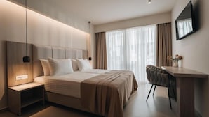 A modern hotel room with a large bed, bedside table, and a desk with a chair. - Golden Coast Suites (Zakynthos)