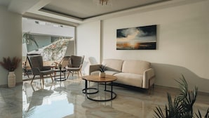 A modern living room with a sofa, chairs, a coffee table, and a painting on the wall. - Golden Coast Suites (Zakynthos)