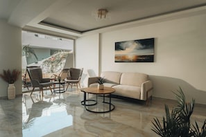 Una sala de estar moderna con un sofá, sillas, una mesa de centro y un cuadro en la pared.