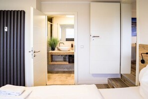 A hotel room with a bed, a bathroom with a sink and mirror, and a view of a snowy landscape. - Holiday apartment 712 (Winterberg)