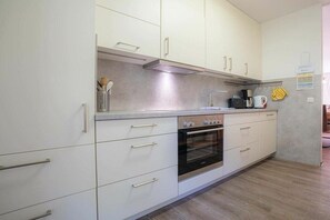 Eine moderne Küche mit weißen Schränken, einem eingebauten Backofen und einer Kaffeemaschine.