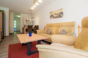 Ein Wohnzimmer mit einer Couch, einem Couchtisch und einem Essbereich mit Stühlen.