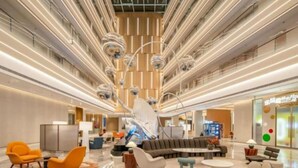 Tilava aula, jossa on keskeisellä paikalla sijaitseva oleskelualue, moderni kattokruunu ja vastaanottotiski.