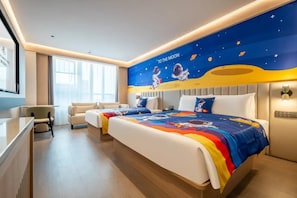 Een hotelkamer met een bed, twee nachtkastjes, een bureau en een stoel. De kamer heeft een groot raam en een muurschildering met astronauten en de maan.
