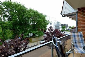 A balcony with a view of trees and a parked car. - 4 in the house Strandläuferweg 10 (ID 018) (St. Peter-Ording)