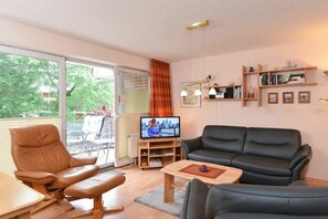 Un salon avec un canapé en cuir, un fauteuil en cuir, un téléviseur et une bibliothèque.