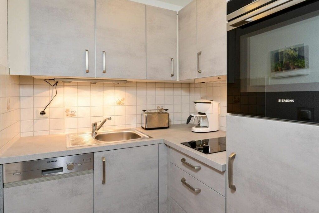 Una cucina moderna con lavastoviglie Siemens, macchina da caffè e tostapane.