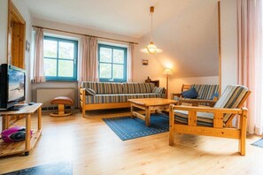 A cozy living room with a sofa, armchair, wooden coffee table, and a television. - OG in the Reimer house (ID 313) (St. Peter-Ording)