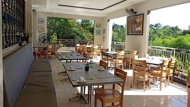 Un restaurante con terraza, mesas, sillas y vistas a zonas verdes.