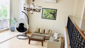 Una sala de estar con un sillón colgante, un sofá, una mesa de centro y un cuadro en la pared.
