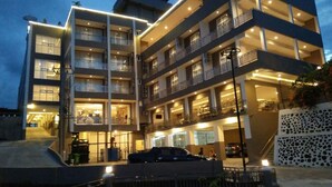 Un hotel de varios pisos con balcones, un estacionamiento y una entrada con portón.