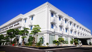A white building with multiple windows and balconies, surrounded by greenery. - Singapore City Hotel (Batu Bara)