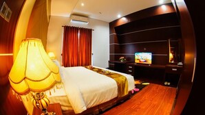 A hotel room with a bed, a TV, a desk, and a lamp. - Singapore City Hotel (Batu Bara)