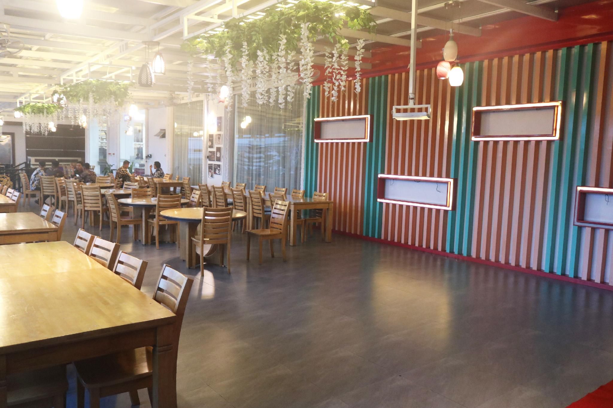A restaurant interior with wooden tables and chairs, striped walls, hanging plants, and pendant lighting.
