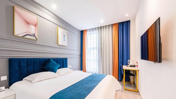 Quarto de hotel com uma cama grande, mesa de cabeceira, escrivaninha e espelho.