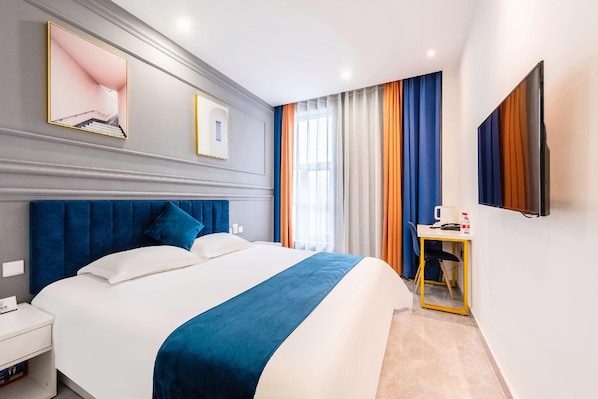 Habitación de hotel con una cama grande, una mesita de noche, un escritorio y un espejo.