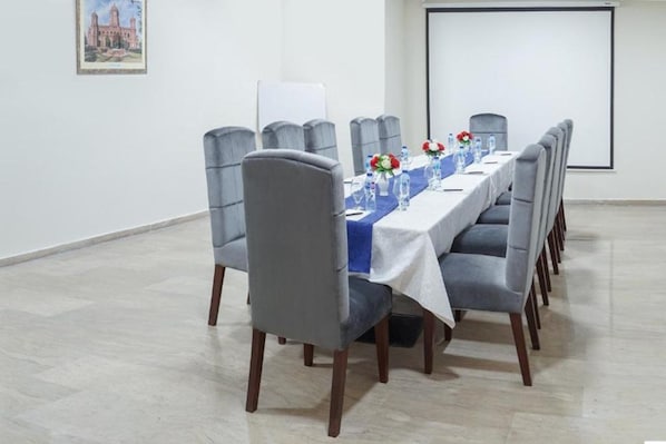 A conference room with a long table, grey upholstered chairs, and a projector screen. - Faletti's Express - Shimla Hill (Lahore)