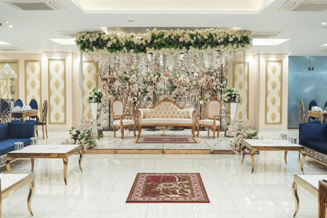 A luxurious hotel lobby with a central seating area, elegant furniture, and decorative floral arrangements.