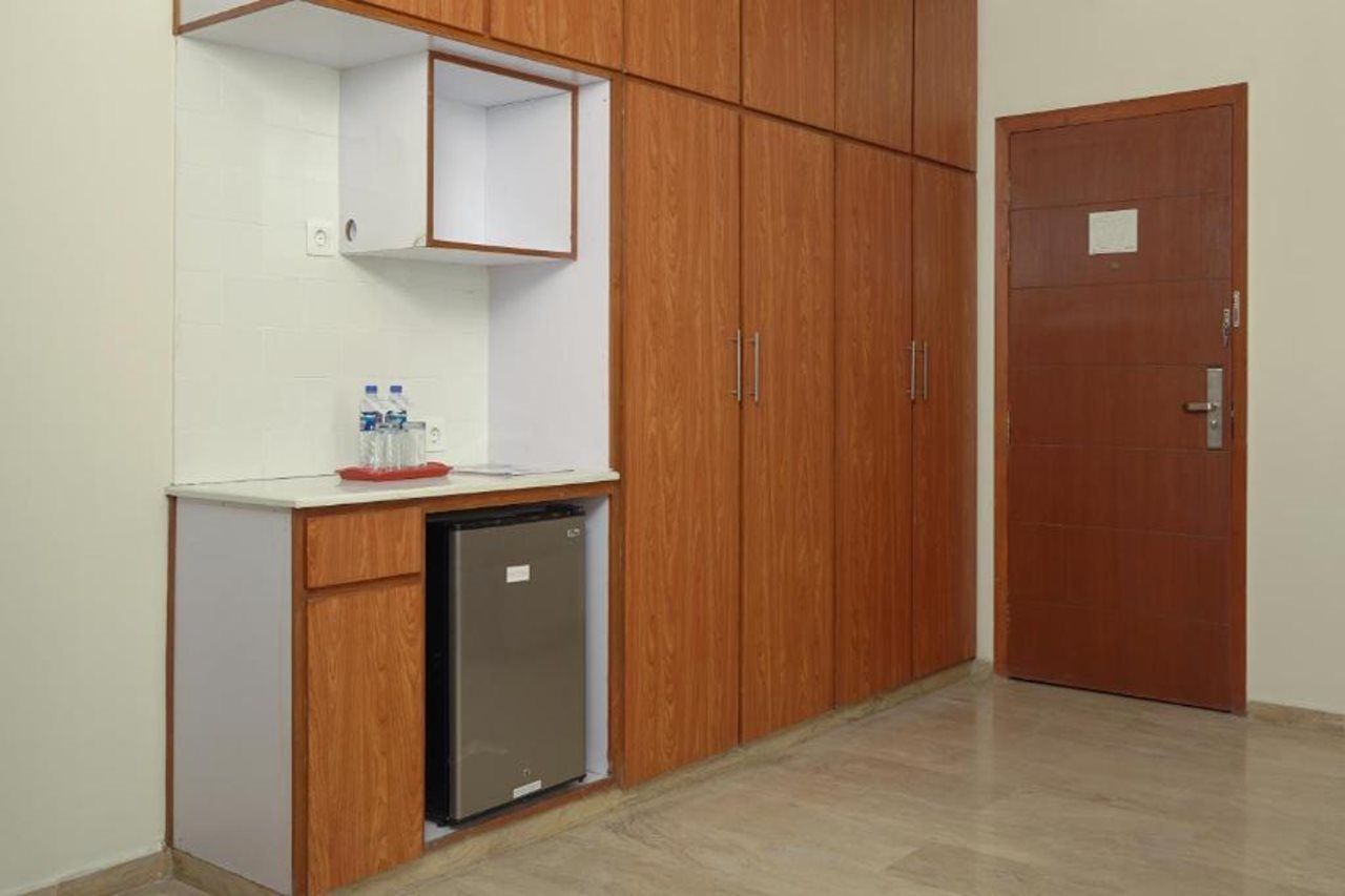 Una kitchenette equipada con un refrigerador empotrado, un lavamanos pequeño y un armario sobre la encimera.