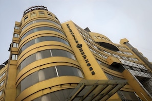 A hotel with a curved facade, multiple balconies, and a prominent vertical sign. - Faletti's Express - Shimla Hill (Lahore)
