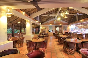 A restaurant with thatched roof ceilings, wooden tables, and chairs. - Hotel Santa Fe Puerto Escondido (Santa María Colotepec)