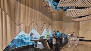 Un área de recepción con diseño moderno, que presenta una pared de madera con un patrón geométrico y un suelo amplio y reflectante.