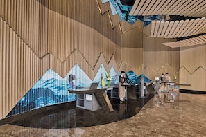 Een receptiezone met een modern design, met een houten wand met een geometrisch patroon en een grote, reflecterende vloer.