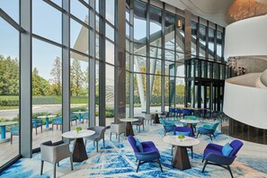 Een moderne binnenruimte met grote ramen, zithoeken en een opvallend architectonisch element.