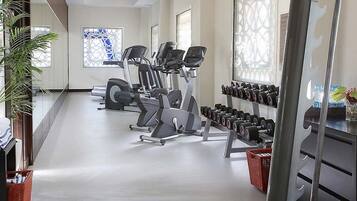A gym with cardio machines, dumbbells, and a mirrored wall.
