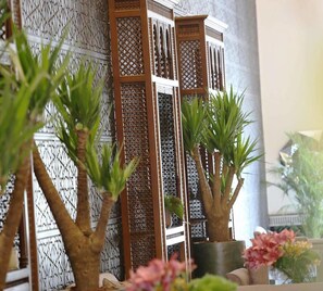 A room with a decorative wooden partition, potted plants, and a vase with flowers. - Sedra Al Alami Jeddah Apartment (Jeddah)