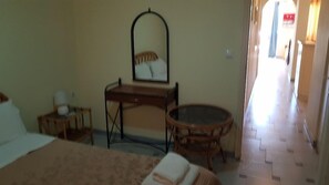 A hotel room with a bed, a round table, a dresser with a mirror, and a small bedside table. - Nefeli Wind Club (Lefkada)