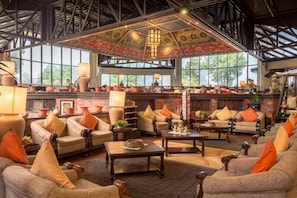 A spacious lounge area with multiple seating options, a fireplace, and large windows offering natural light. - Club Himalaya by ACE Hotels (Baluwapati Deupur)