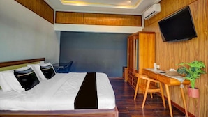 A hotel room with a bed, a desk, a chair, a television, and a potted plant. - Collection O Near Sanur Beach Formerly Sutji Living (Denpasar)