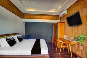 Ein Hotelzimmer mit einem Bett, einem Schreibtisch, einem Sessel, einem Fernseher und einer Topfpflanze.