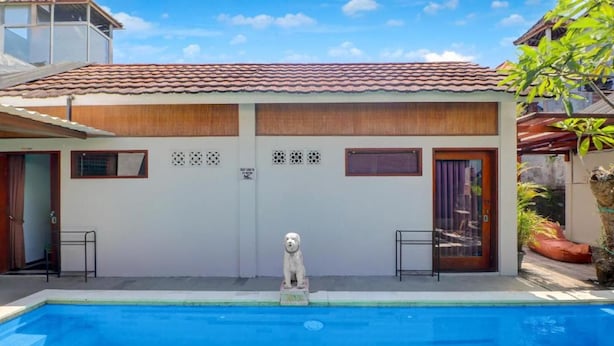 A swimming pool with a statue in the center, surrounded by a building with a tiled roof and a small garden area. - Collection O Near Sanur Beach Formerly Sutji Living (Denpasar)