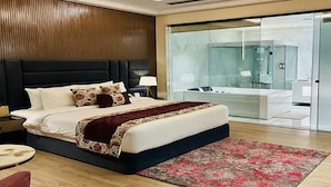 Un dormitorio moderno con una cama grande, zona de ducha con mampara de vidrio y vistas a la ciudad.
