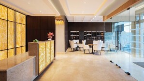 Un moderno vestíbulo de hotel con mostrador de recepción, zona de estar y paredes de vidrio.