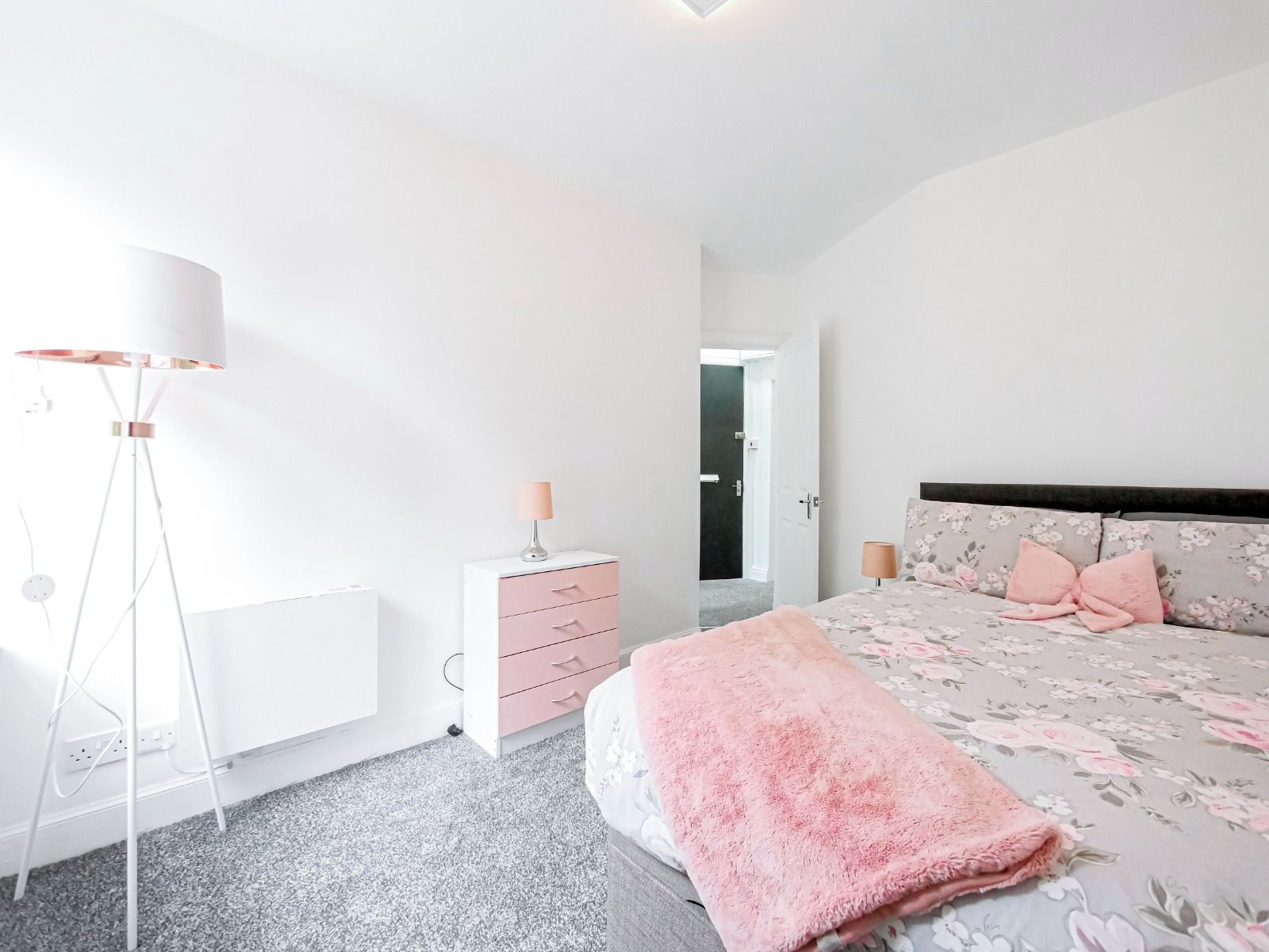 A bedroom with a bed, bedside lamps, a dresser, and a floor lamp.