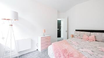 A bedroom with a bed, bedside lamps, a dresser, and a floor lamp.