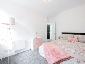 Ein Schlafzimmer mit einem Bett, Nachttischlampen, einer Kommode und einer Stehlampe.