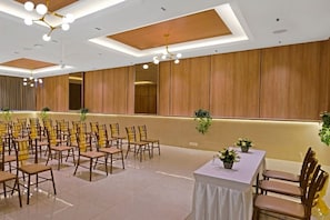 A conference room with rows of chairs, a table with a white tablecloth, and a ceiling with recessed lighting. - Click Hotel Biz Bangalore (Bengaluru)