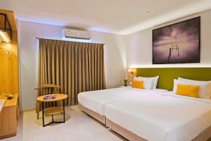 A hotel room with a large bed, a small table with a chair, an air conditioning unit, and a painting on the wall. - Click Hotel Biz Bangalore (Bengaluru)