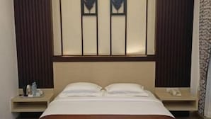 A hotel room with a large bed, bedside tables, and a headboard with vertical panels. - Dawala Hotel (Makassar)